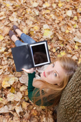 Beautiful young woman with tablet in autumn park