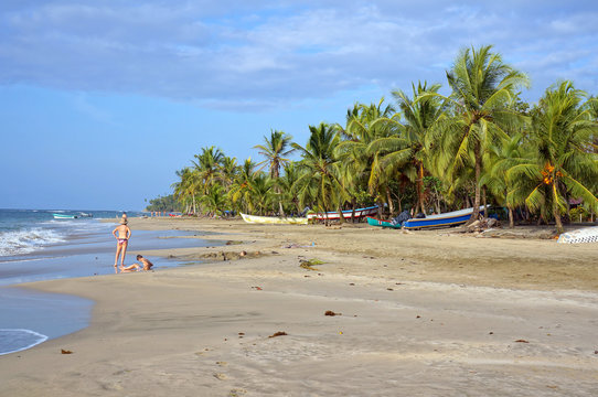 Caribbean beach with few tourists and fishing boats under coconut trees, Manzanillo, Costa Rica, Central America