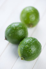 Vertical shot of three fresh lime fruits on wooden boards