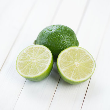 Ripe lime and its halves on wooden boards, close-up