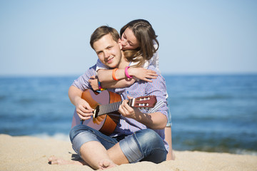 Portrait of young man with guitar and woman on a beach