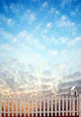 white fence with bird house and blue sky