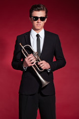 Fototapeta premium Retro fifties trumpet player wearing black suit and sunglasses.