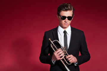 Fototapeta premium Retro fifties trumpet player wearing black suit and sunglasses.