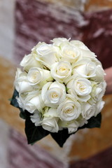 A bride holds her bouquet of white roses