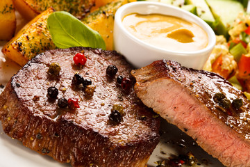 Grilled steak, baked potatoes and vegetables