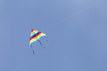 A colorful triangular kite flying in the sky