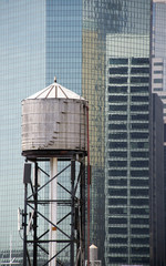 Water tower in front of modern glass building in New york city