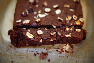 Chocolate brownie with hazelnuts, sliced, detail on baking paper