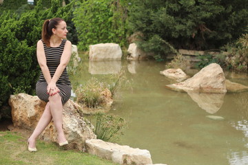 Pretty brunette woman sitting near the lake, posing