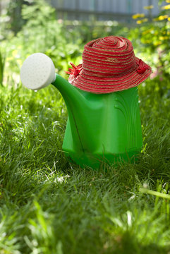 garden watering can and a hat