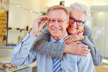 Happy senior couple with new glasses at optician