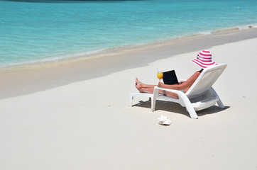 Fototapeta na wymiar Girl with a laptop on the tropical beach. Exuma, Bahamas