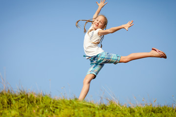 little girl jumping over the grass