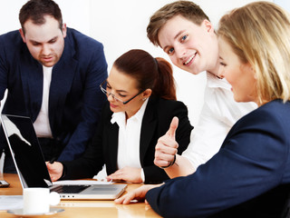 Business people are in a meeting, one shows thumb up