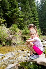 Naklejka na ściany i meble Little girl playing by a forest stream