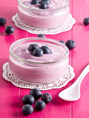 Joghurt mit Heidelbeeren auf einem Holztablett.