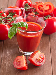 Tomatensaft mit frischen Tomaten im Hintergrund.