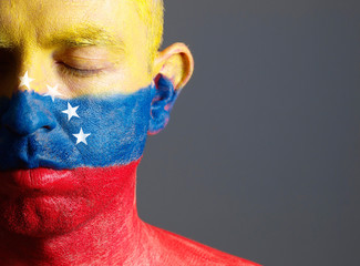 Man and his face painted with the flag of Venezuela and closed e