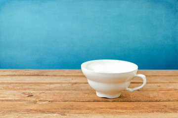 Empty coffee cup on wooden table over blue background