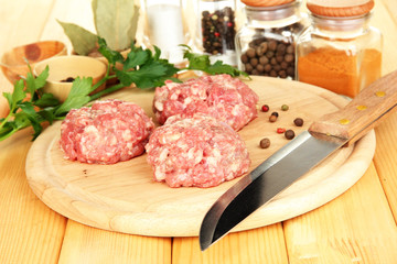 Raw meatballs with spices on wooden table