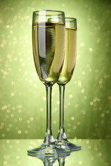 Two glasses of champagne on bright background with lights