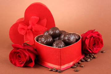 Chocolate candies in gift box, on brown background