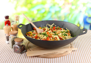 Noodles with vegetables on wok on nature background
