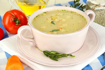 Nourishing soup in pink pan on wooden table close-up