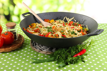 Noodles with vegetables on wok on nature background