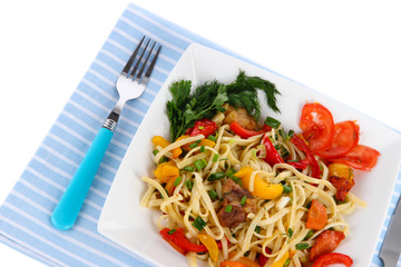 Noodles with vegetables on plate on napkin isolated on white