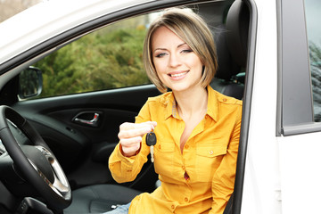 Portrait of happy beautiful woman with car key, sitting in the