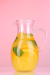 Orange lemonade in pitcher on pink background