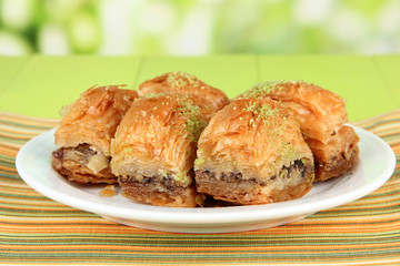 Sweet baklava on plate on table on bright background
