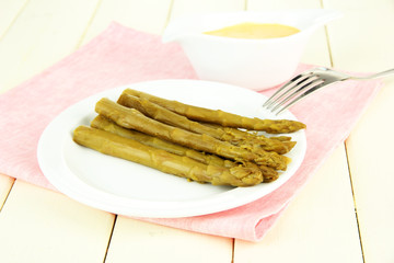 Asparagus on plate, on wooden background