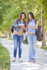 Obraz premium Young Adult Mixed Race Twin Sisters Sharing Cell Phone Experienc
