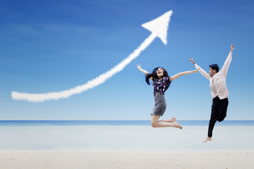 Happy partners jump under increase arrow sign cloud at beach
