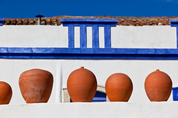 Clay pots stand on white pottery wall in Portugal