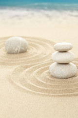 Balance zen stones in sand with sea in background