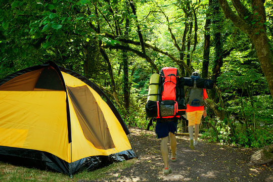 yellow tent and tourists with backpacks - Powered by Adobe