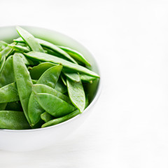 Snow peas in white bowl with copy space