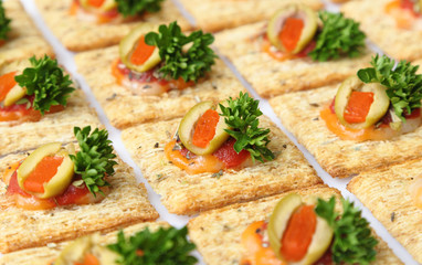 Baked wheat crackers topped with cheese, olives, and parsley