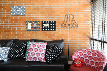 Colorful pillows on a sofa with brick wall in background