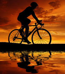 Fototapeta premium silhouette of the cyclist riding a road bike at sunset