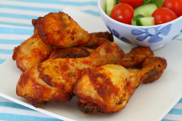 Roasted chicken drumsticks on vintage plate, close up