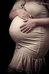 Portrait of pregnant woman touching her belly with hands