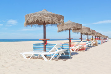 Wooden beach umbrellas and sunbeds on the beach. For the holiday