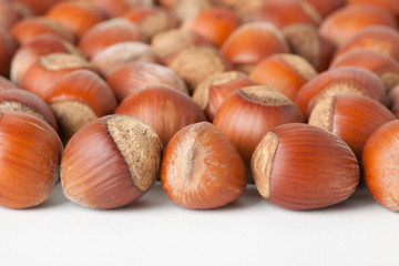 Unbroken hazelnuts on white surface