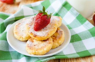 cheese pancakes with powdered sugar and strawberries