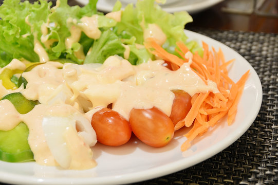 Fresh vegetable salad in white bowl topped with thousand island